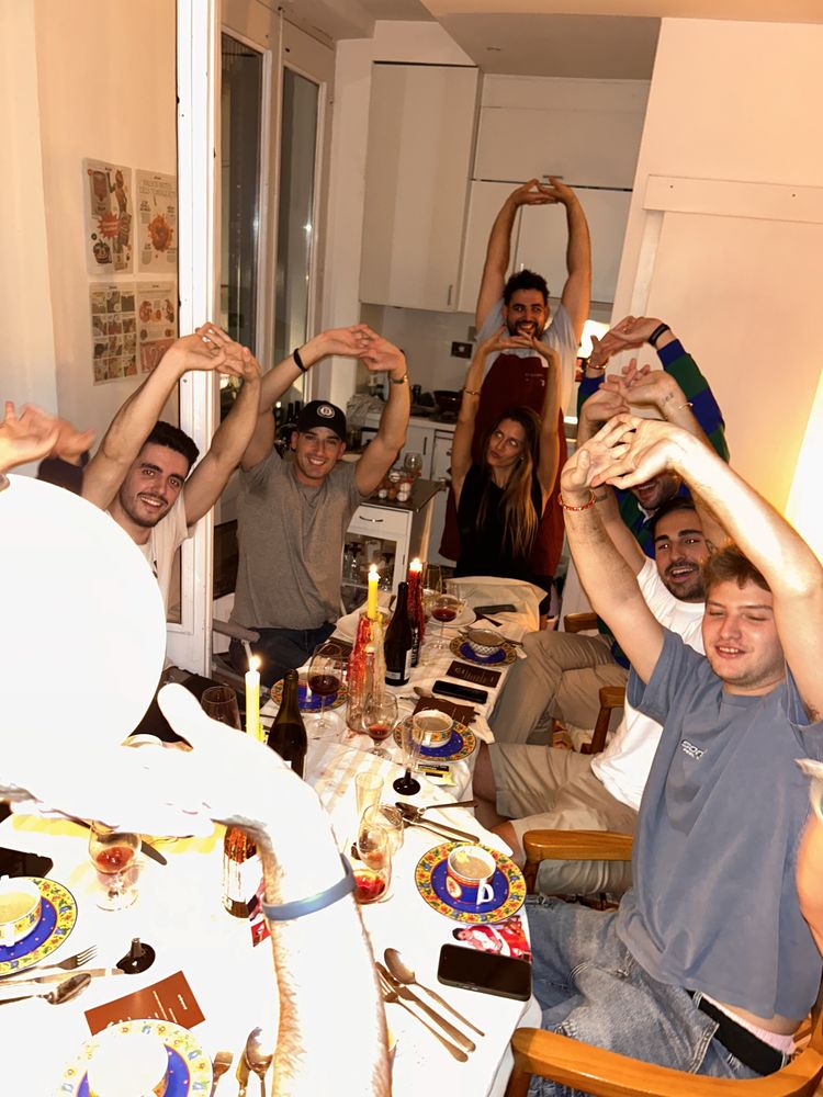 Cena en casa con los invitados levantando los brazos
