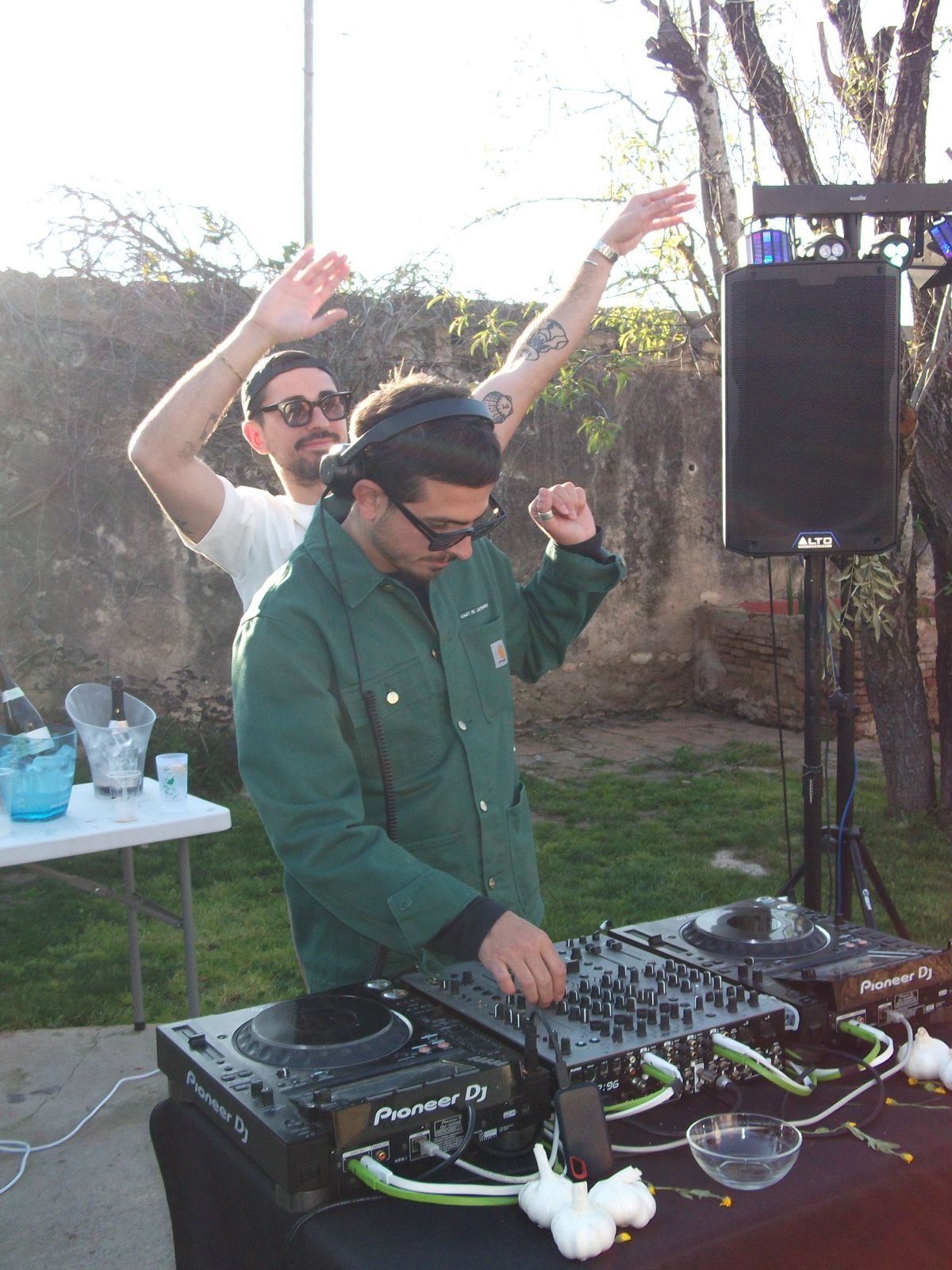 DJ pinchando al aire libre mientras alguien levanta los brazos